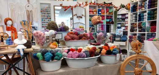 Interior of Big Bear Yarn Co with colorful yarn display and spinning wheel