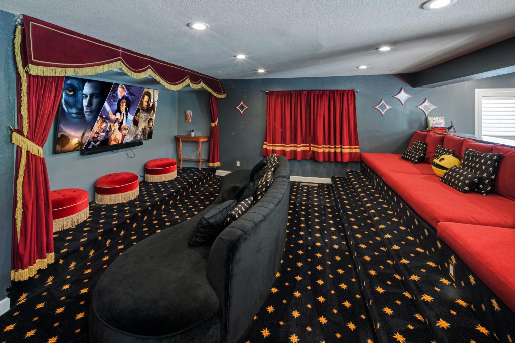Cozy home theater in Bigfoot cabin with red couches and a red curtain, designed for an immersive viewing experience.