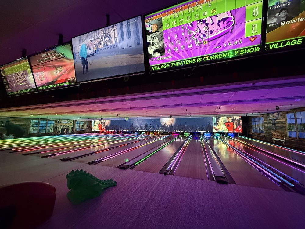 Colorful glow bowling lanes with score screens at The Bowling Barn