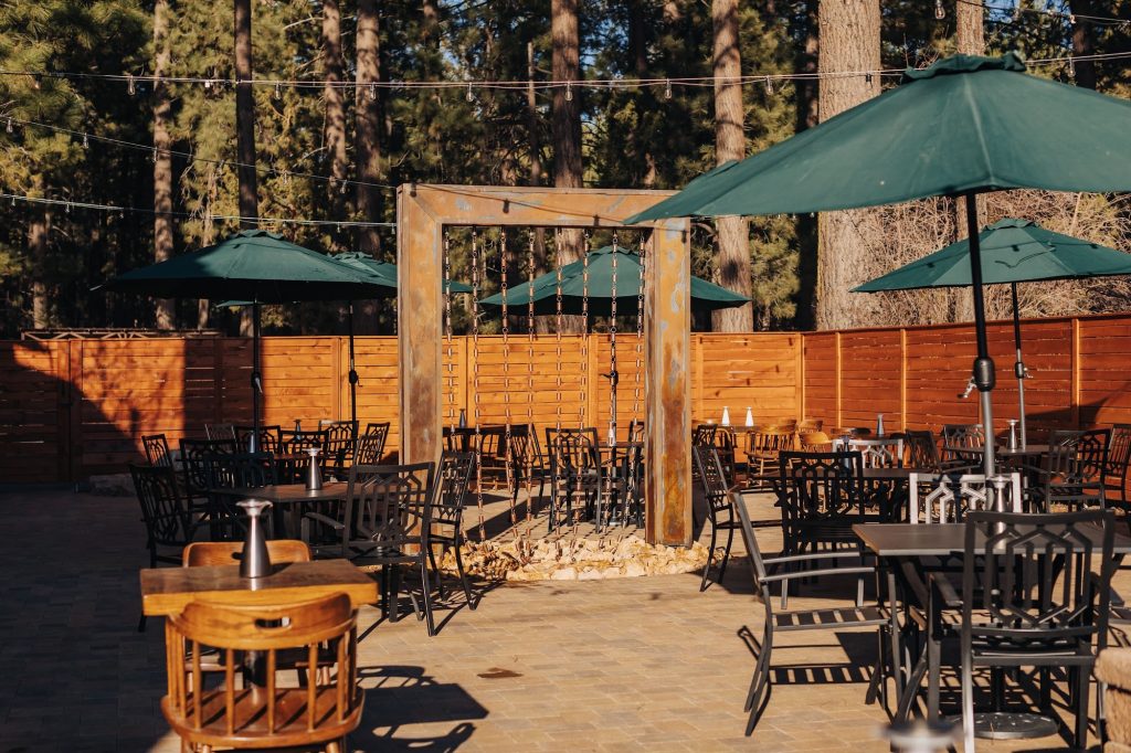 Captain’s Anchorage outdoor patio seating in Big Bear Lake with umbrellas and forest surroundings