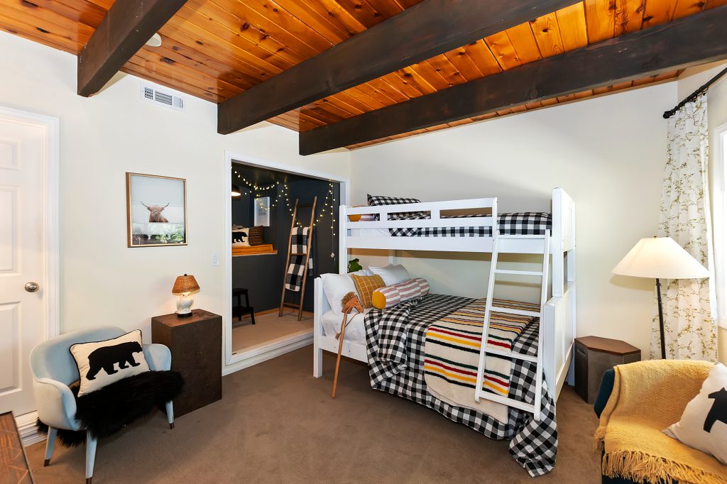 A cozy bedroom with a bunk bed, exposed wooden beams, and rustic decor in Big Bear.