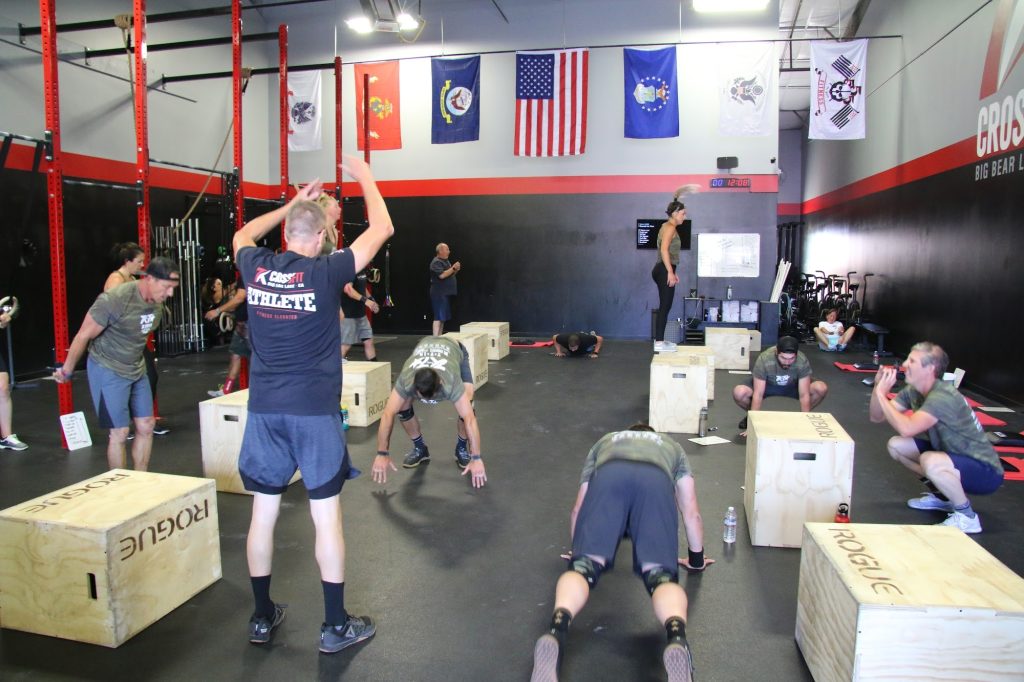 Indoor CrossFit class with athletes performing strength and conditioning exercises using rigs and equipment