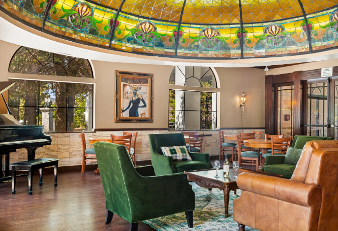 Elegant lounge with stained glass dome ceiling, piano, comfortable seating, and dining tables