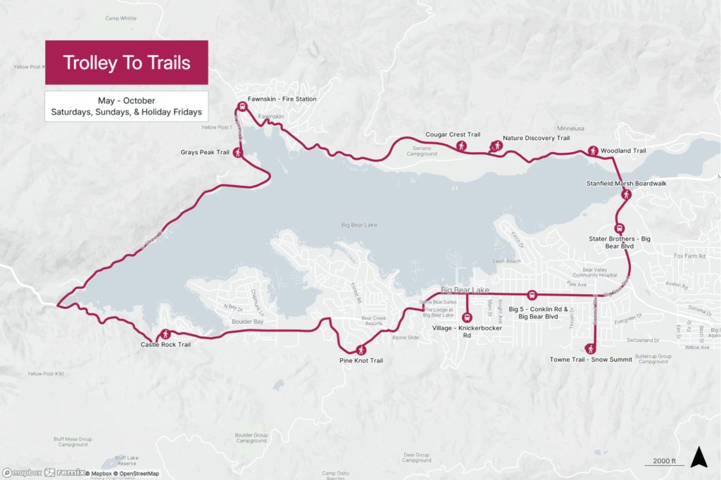 Map showing the Trolley To Trails route around Big Bear Lake, highlighting key stops like Grays Peak Trail, Cougar Crest Trail, Pine Knot Trail, and more, available from May to October on weekends and holiday Fridays.