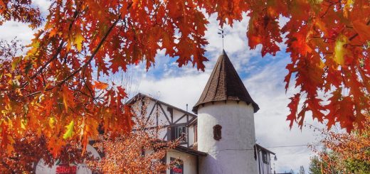 A building with a conical tower is framed by bright orange and red autumn leaves in Big Bear.