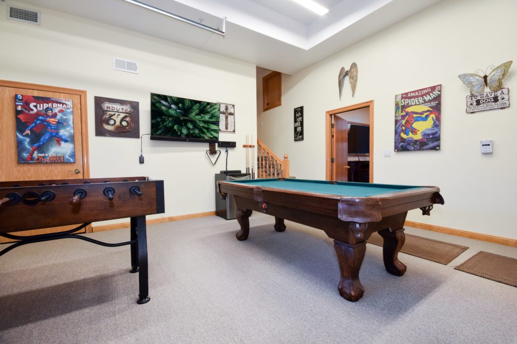A Big Bear game room featuring a foosball table, a billiards table, and comic book posters on the walls.