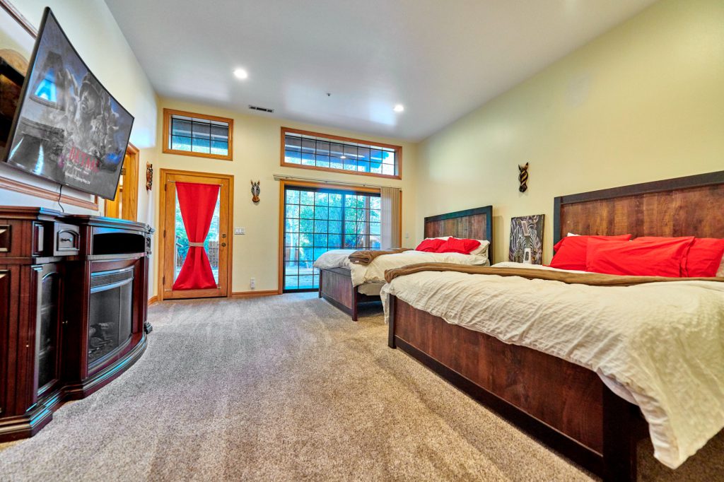 A cozy bedroom with two beds, a fireplace, and a large TV on the wall in Big Bear.