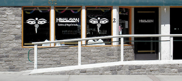 A wide-angle shot of the front of a restaurant with a sign that reads "Himalayan Cuisine of Nepal & India," with an accessibility ramp and a stone facade at Big Bear.