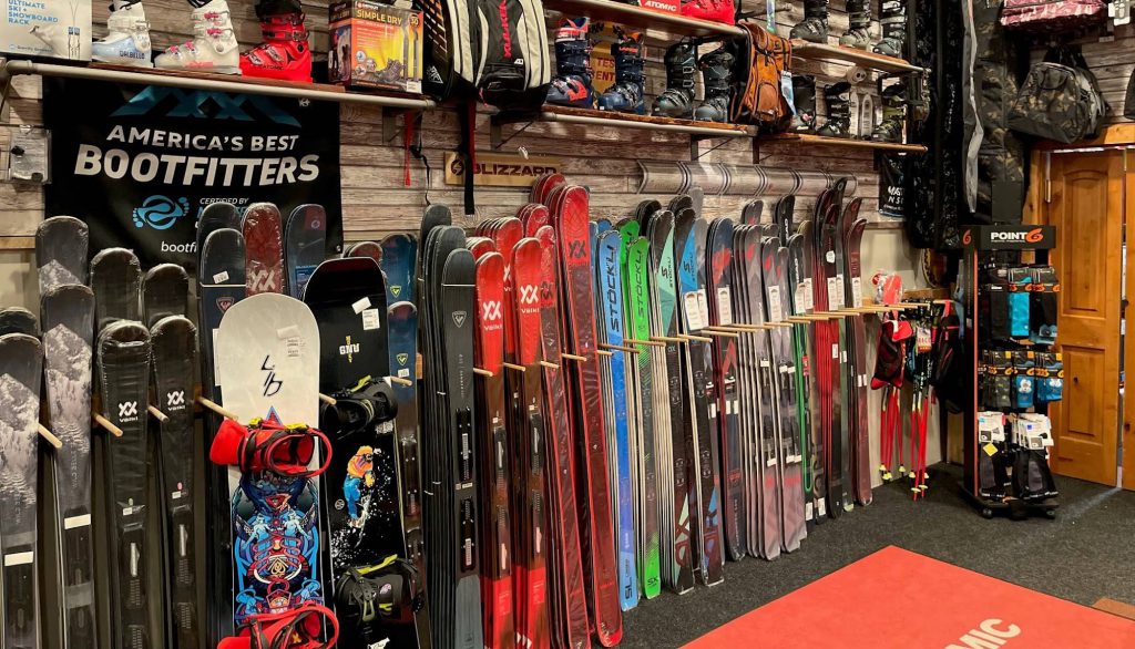 Interior of Goldsmiths Sports in Big Bear Lake featuring ski and snowboard rentals displayed along a wooden wall with America’s Best Bootfitters sign.