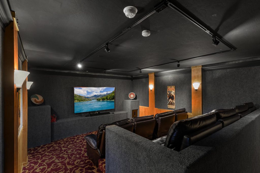 A private home theater in Grand Cameron Estate, Big Bear, featuring a couch and a large television for an immersive viewing experience.