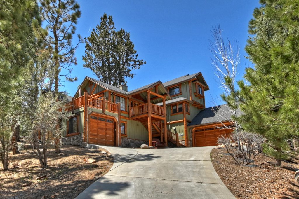 Exterior view of a spacious Highland Manor cabin in Big Bear, with a driveway extending towards the front door.