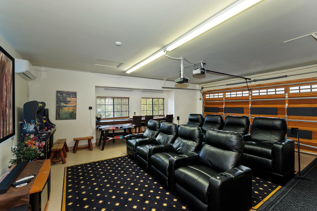 Home theater room in Highland Manor cabin, Big Bear featuring black leather seats and a plush black rug.