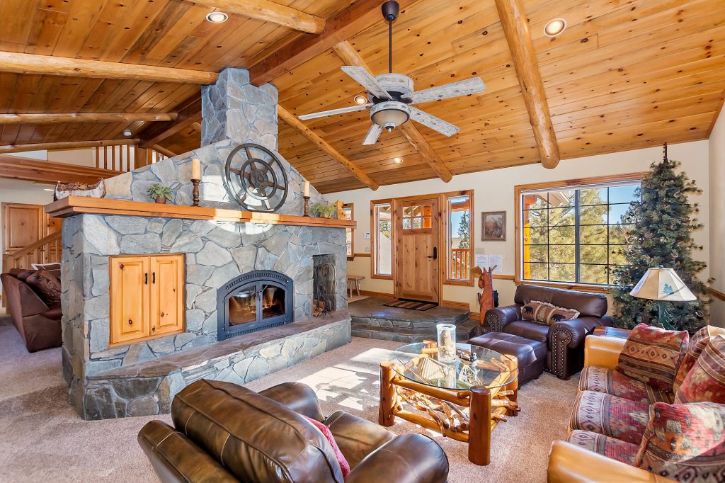 Cozy living room in Highland Manor cabin, Big Bear featuring a stone fireplace and comfortable couches.