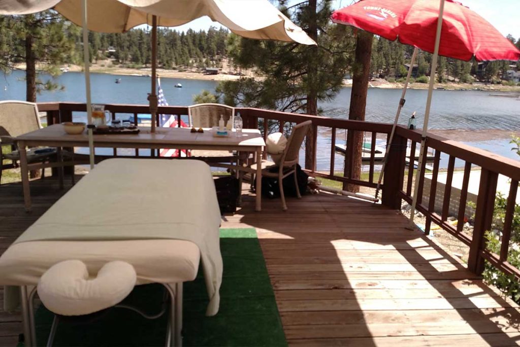 Relaxing outdoor massage setup with a peaceful lake view and mountain scenery.