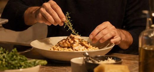 Chef garnishing a freshly prepared gourmet pasta dish with herbs