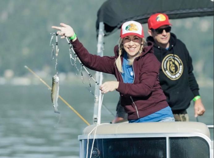 Two people on a pontoon boat showing a fish catch while enjoying a fishing trip on Big Bear Lake