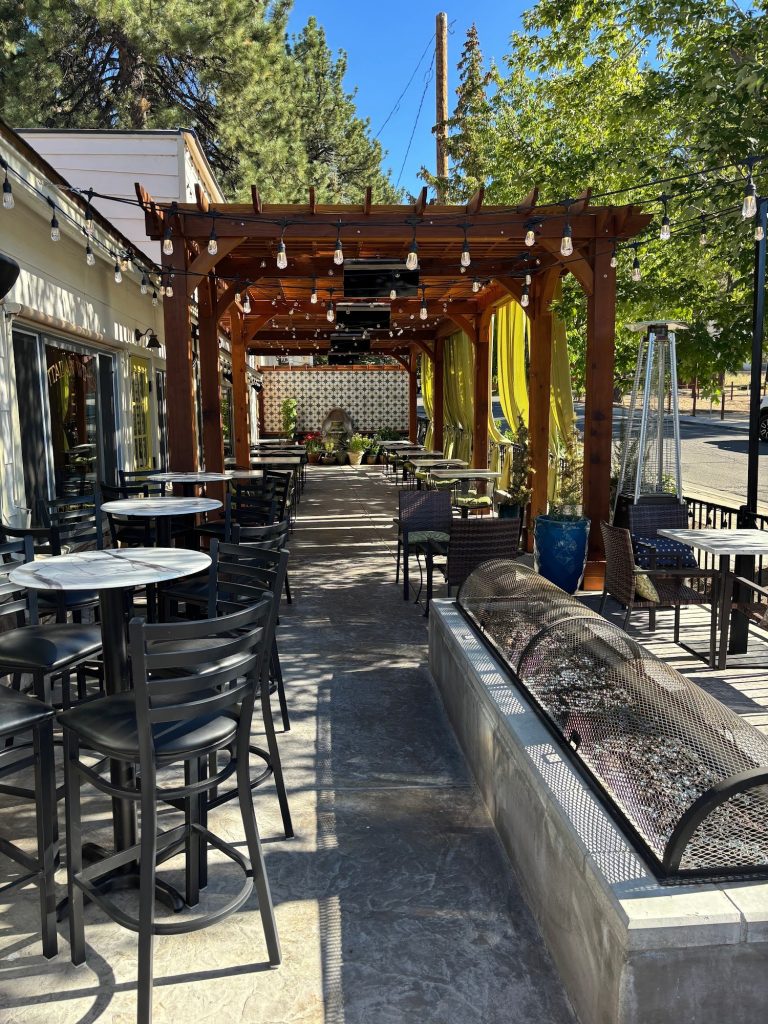 Covered outdoor seating area at La Pergola Trattoria with wooden pergola