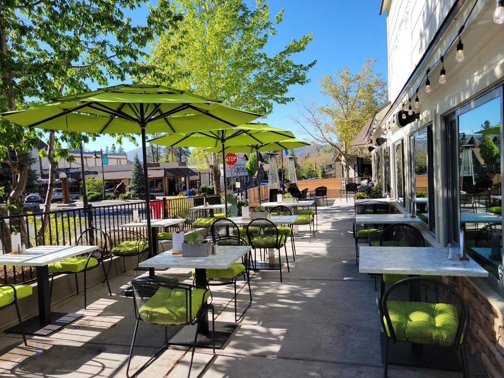 Outdoor patio seating at La Pergola Trattoria in Big Bear with green umbrellas