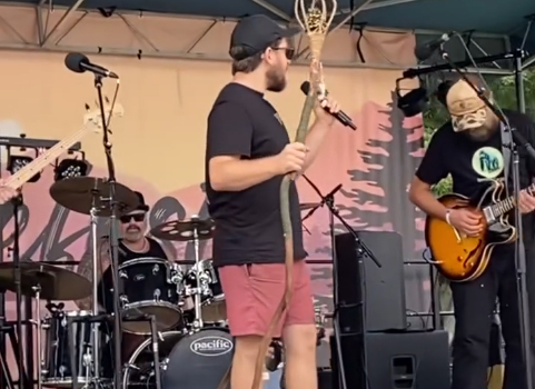 Musicians performing live on stage during the Lakefest open mic event with instruments and microphones