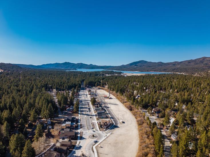 Aerial view of the Moonridge neighborhood with Big Bear Lake, pine forests, and surrounding mountains in the distance.