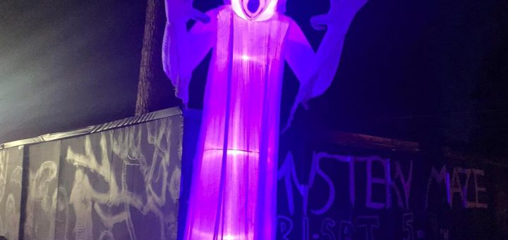 Glowing ghost decoration illuminated in purple light at Mystery Maze in Big Bear