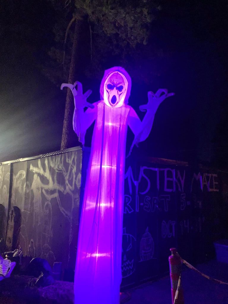 Glowing ghost decoration illuminated in purple light at Mystery Maze in Big Bear