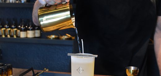 A person pouring liquid wax into a container while making candles at Mystic Moto.