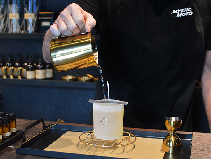 A person pouring liquid wax into a container while making candles at Mystic Moto.