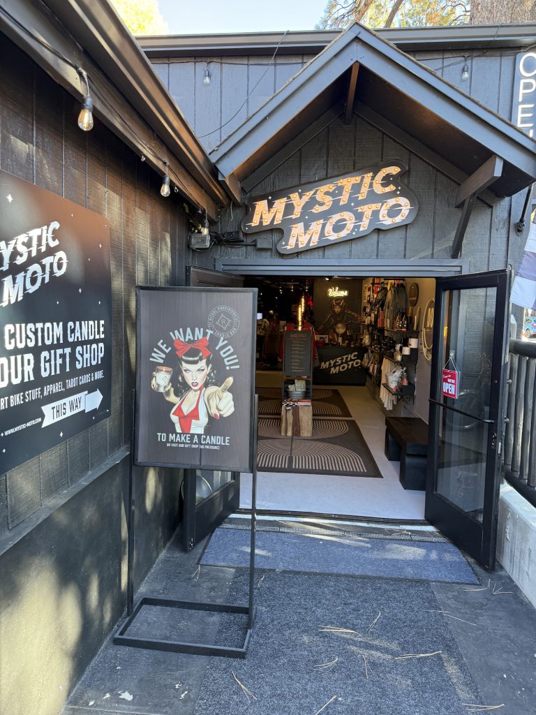 The storefront of Mystic Moto, featuring the shop sign and a welcoming sign about candle-making at Big Bear Lake.