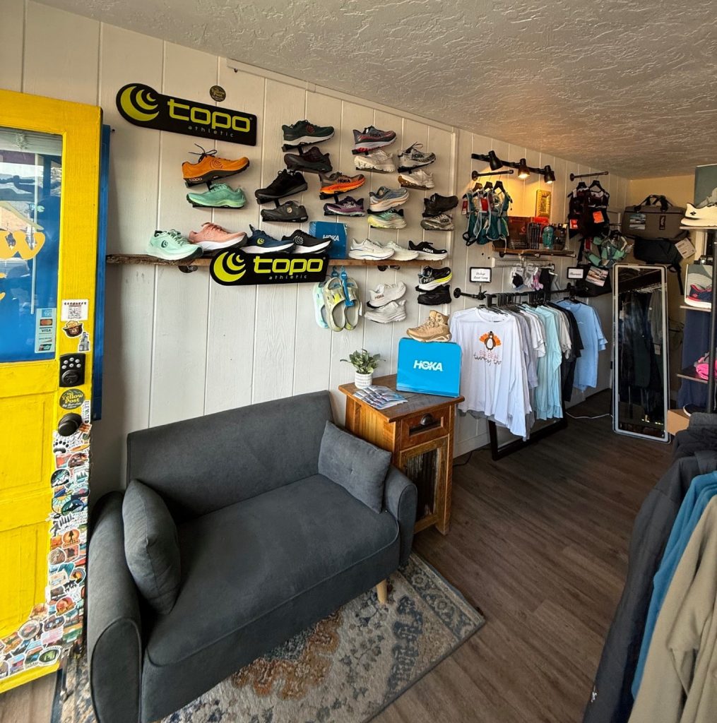 Interior retail shoe store showing wall-mounted footwear displays and organized outdoor shoes section.