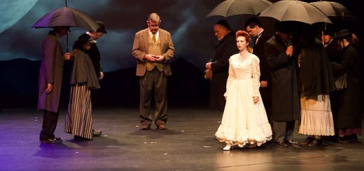A group of performers on stage at Big Bear Theatre Project, each holding colorful umbrellas during a lively performance.