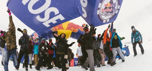 Snowboarders celebrating under a giant Red Bull Roll the Dice inflatable dice at Bear Mountain during a snowy event in Big Bear.