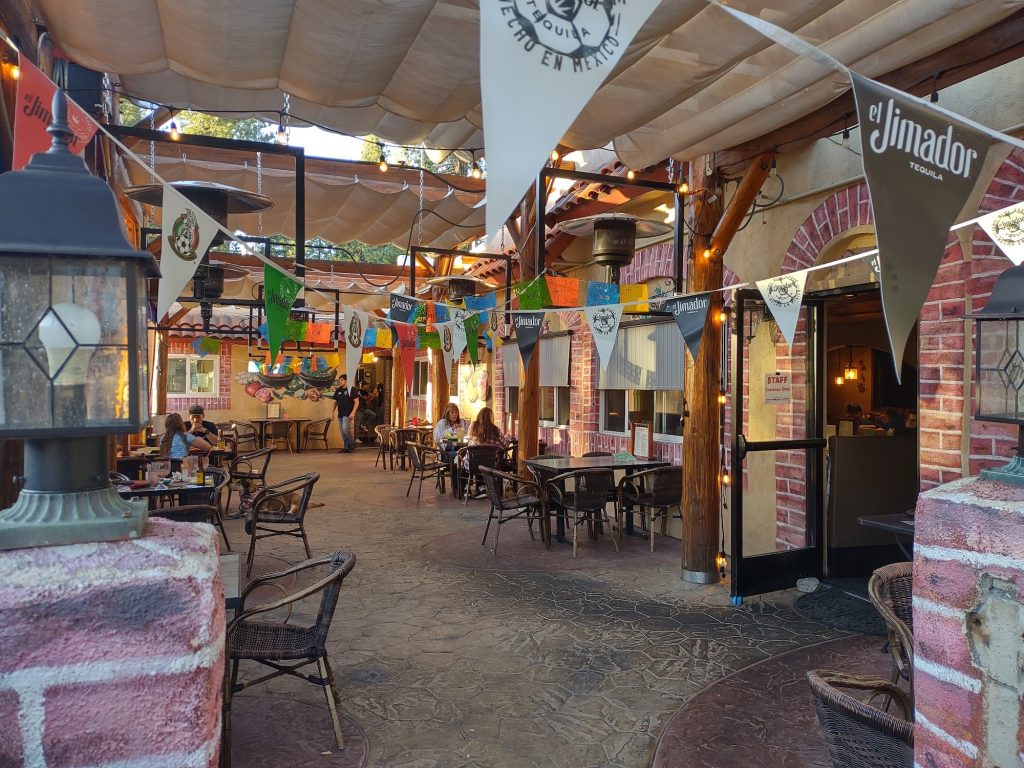 Outdoor patio dining area at Sonora Cantina decorated with festive Mexican banners and string lights.
