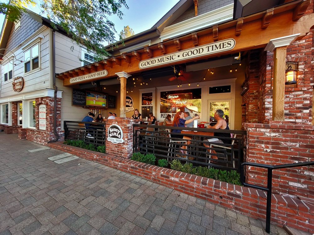 Outdoor patio dining area at Saucy Mama’s Pizza and Beer restaurant with guests enjoying food in Big Bear Lake