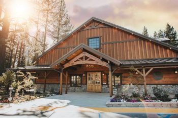 Exterior view of Sunnybrook Lodge featuring a rustic wooden building, mountain surroundings, trees, and a welcoming entrance area