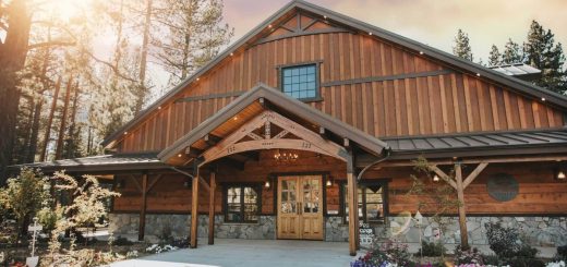 Exterior view of Sunnybrook Lodge featuring a rustic wooden building, mountain surroundings, trees, and a welcoming entrance area