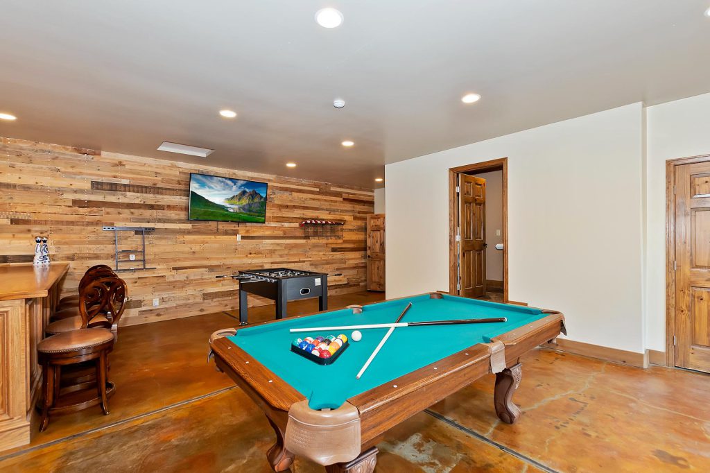 A cozy game room with a pool table, foosball, bar seating, and TV in Big Bear.