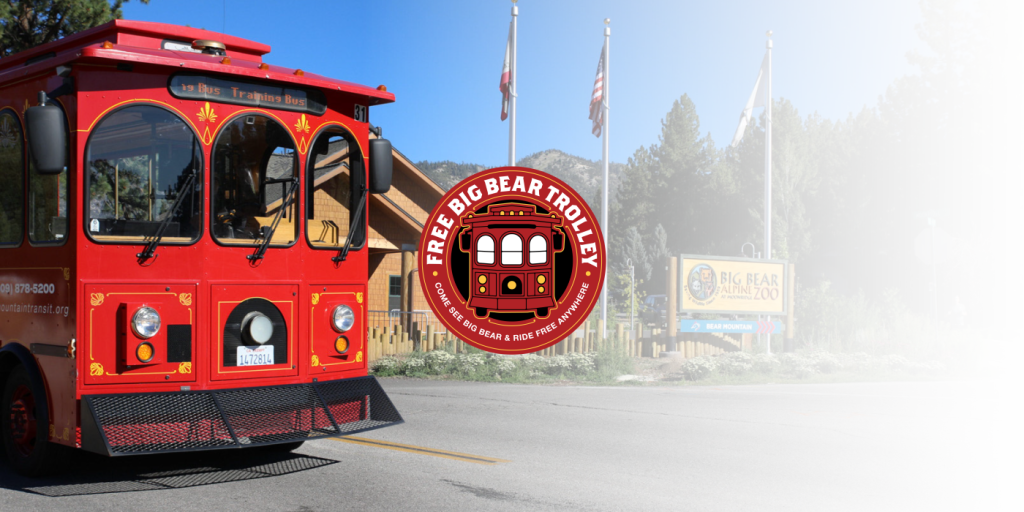 A red Big Bear Trolley bus is parked on a street in Big Bear near the Big Bear Zoo
