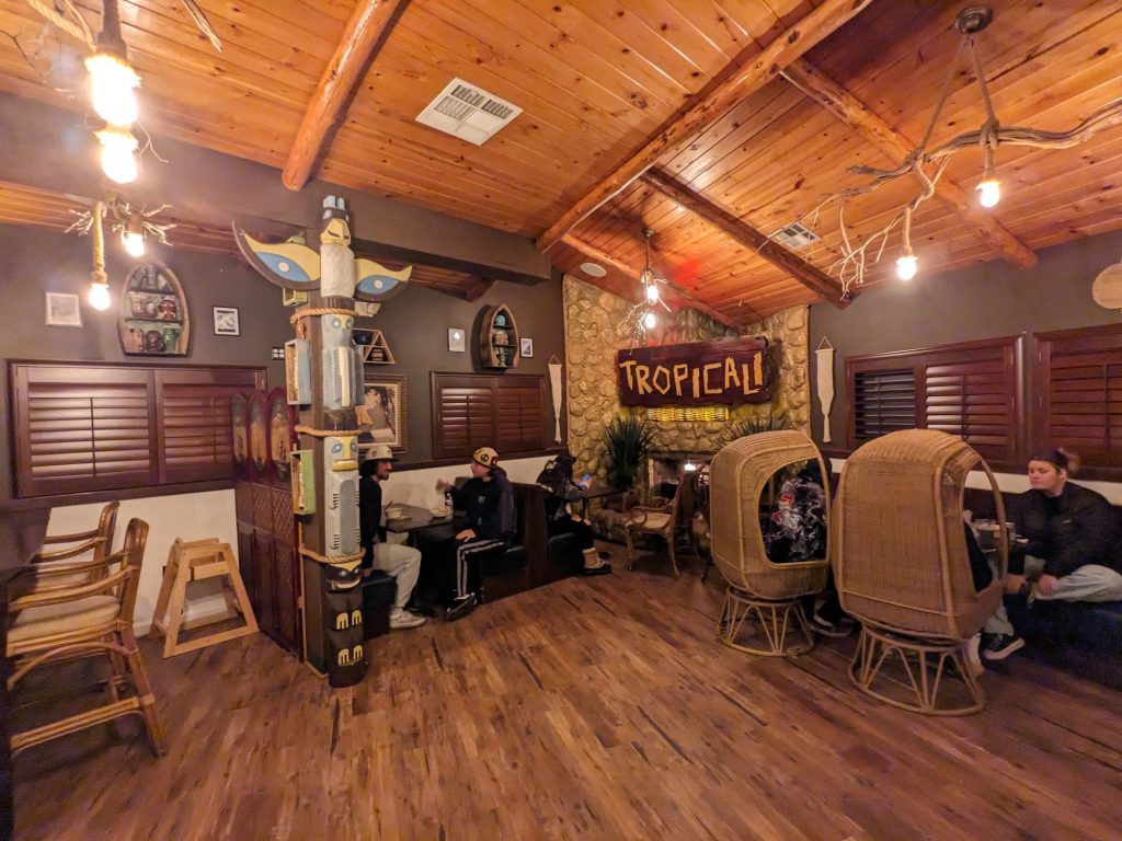 Tropicali restaurant interior with cozy fireplace seating and tiki decor in Big Bear