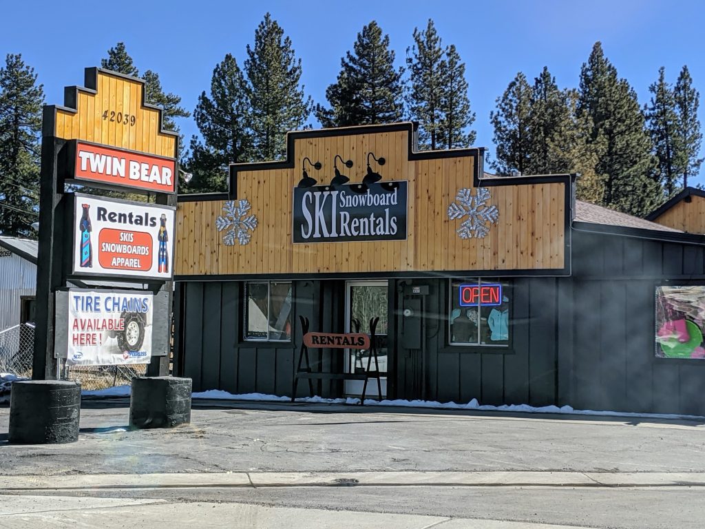 Exterior of Twin Bear Ski & Snowboard Rentals in Big Bear featuring rental signage for skis, snowboards, apparel, and tire chains.