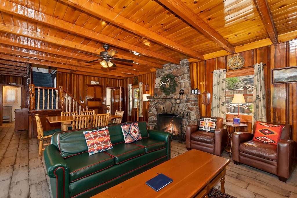 Rustic Big Bear cabin living room with wood-burning fireplace, leather seating, and warm wood interior